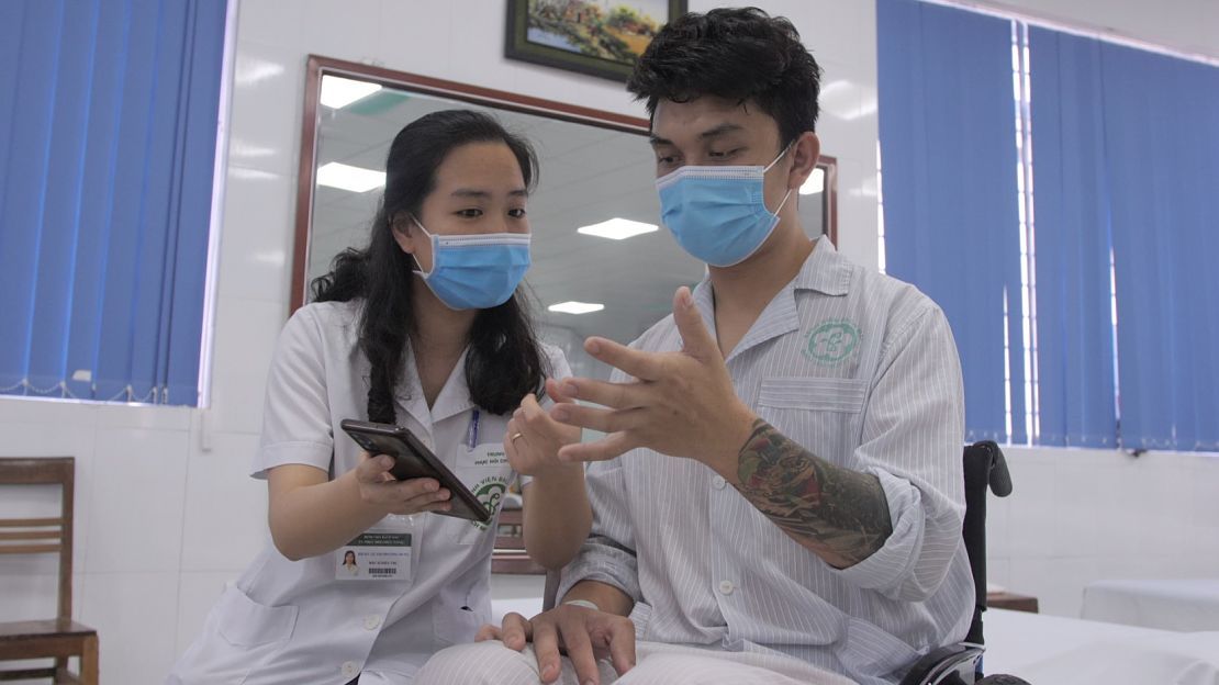 Une kinésithérapeute montre à un patient comment pratiquer des exercices fonctionnels en utilisant l’application OpenTeleRehab, Vietnam 2021. © C. Bachelerie / HI