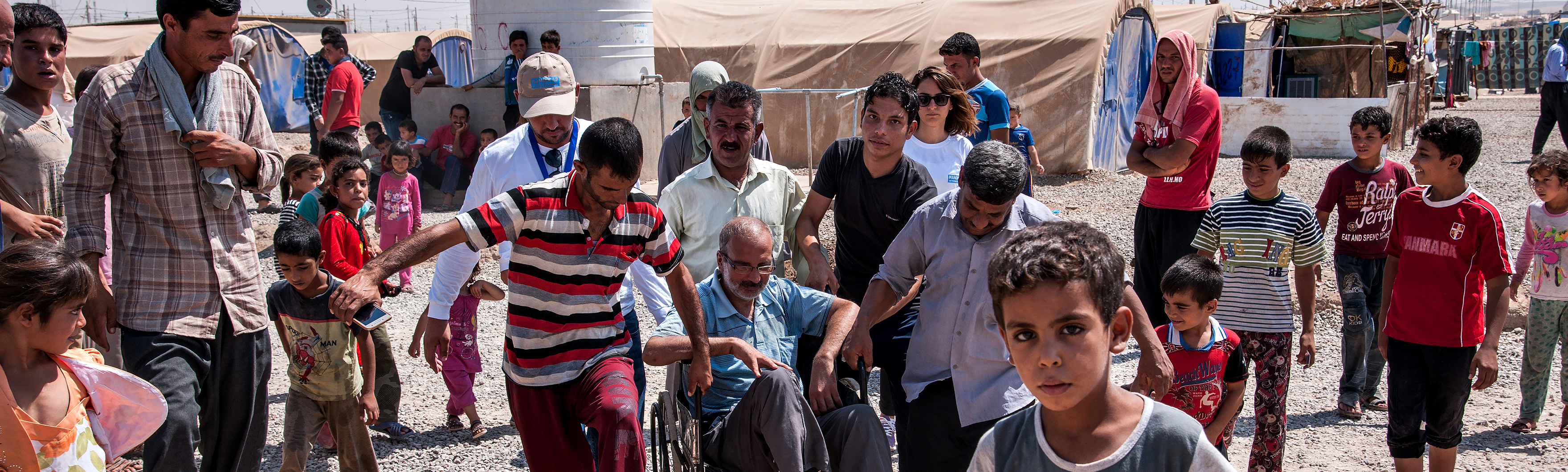 Irak, camp Khazer M1, une équipe psychosociale de HI évalue avec un bénéficiaire les difficultés pour se déplacer dans le camp avec un fauteuil roulant.