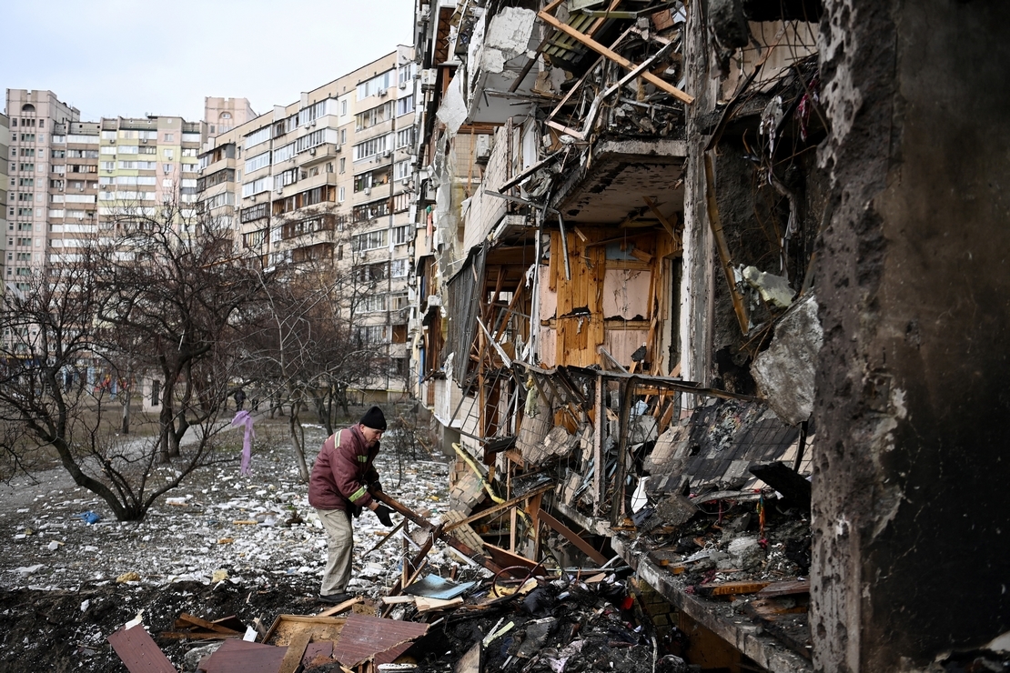Un homme dégage les débris d'un bâtiment résidentiel endommagé dans la rue Koshytsa, une banlieue de la capitale ukrainienne Kiev, frappé par un obus militaire le 25 février 2022. 