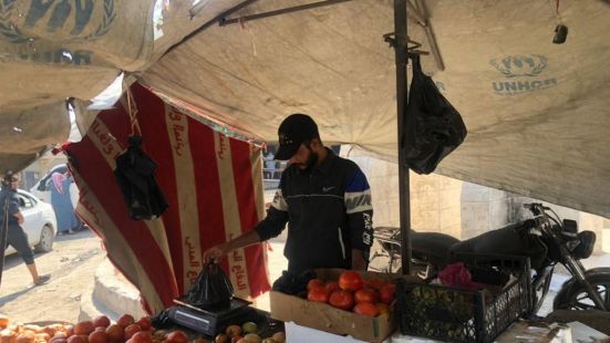 Au marché, un homme en train de peser des fruits