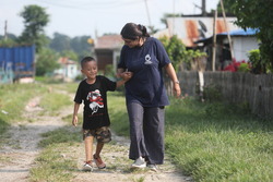 Prabin marche sur une route avec Ambika, orthoprothésiste. © A.Thapa / HI