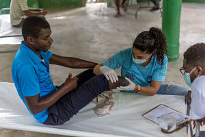 Conseulo accompagne le patient Dieujuste dans une rotation d’equipe mobile après son amputation suite au tremblement de terre. 