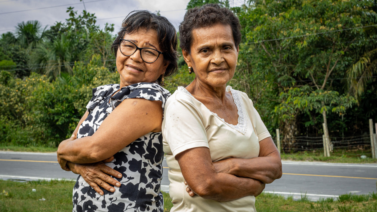 Deux femmes se tiennent dos à dos, dans une attitude de pouvoir et regardent la caméra en souriant.