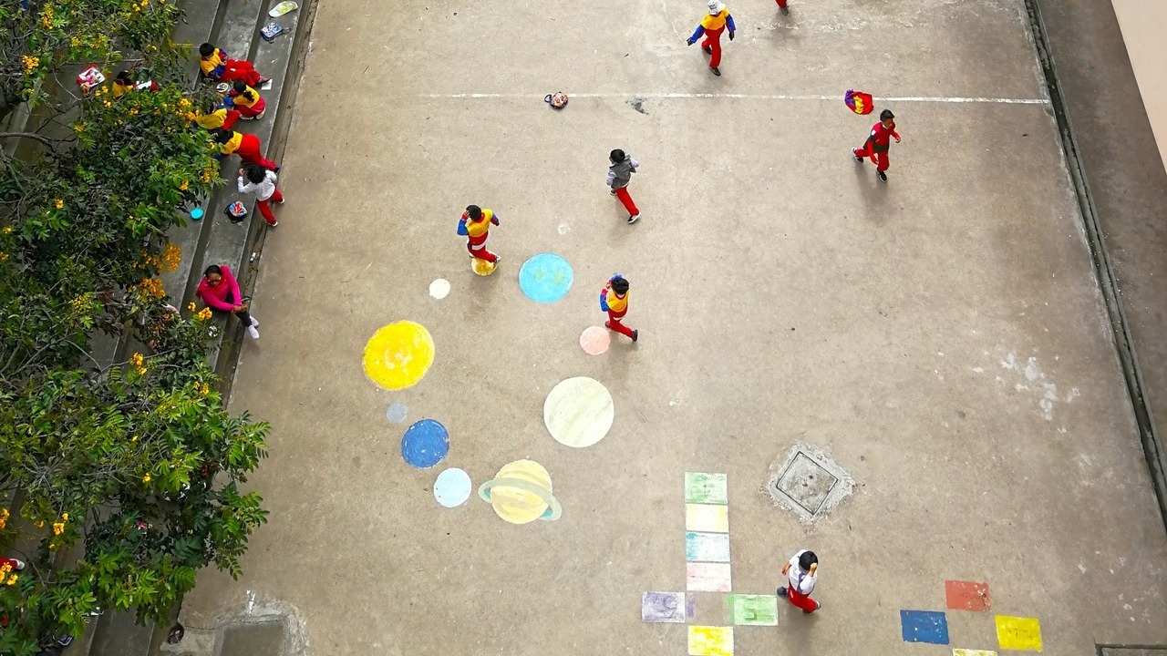 Image aérienne d'une cours d'école dans laquelle jouent des enfants.
