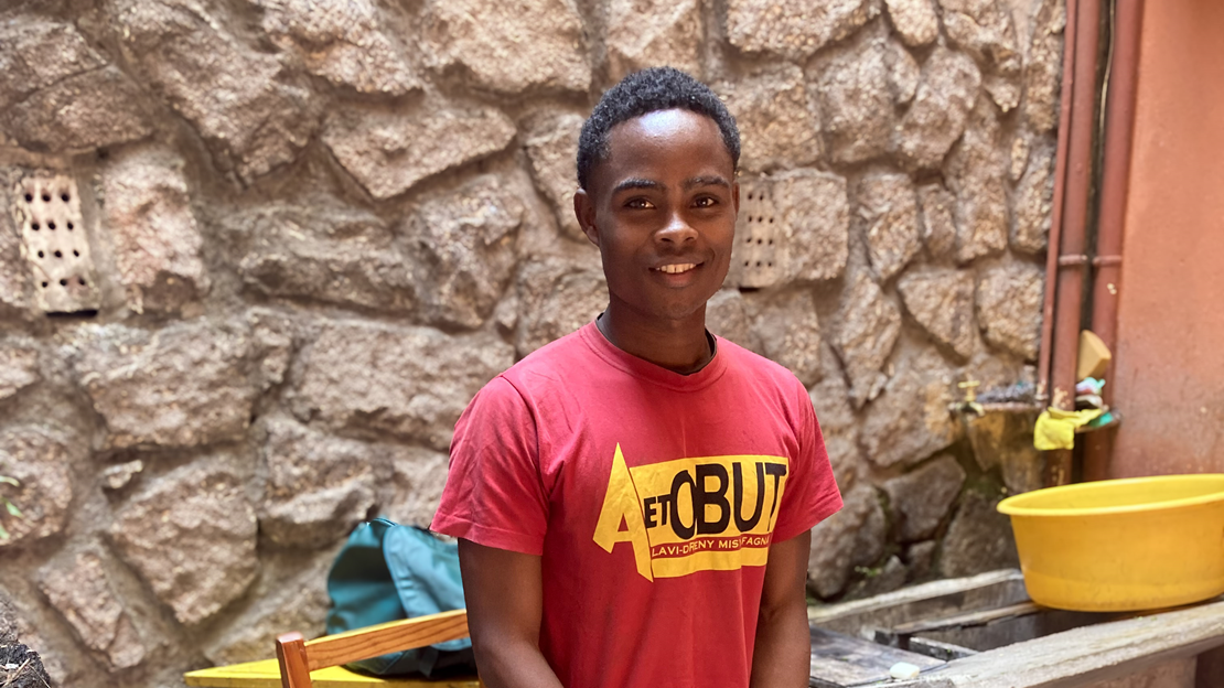 Un jeune homme, bénéficiaire d'une prothèse reconditionnée, se tient debout dans les locaux de HI Madagascar.; }}