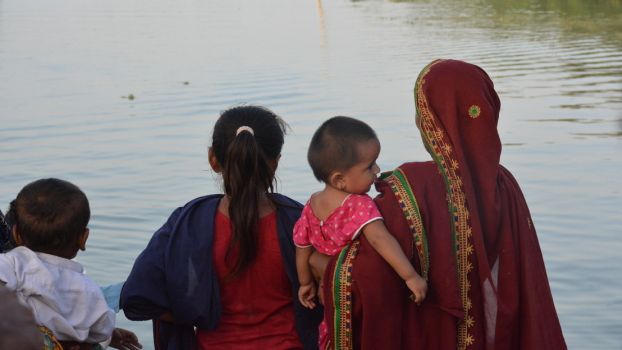 Une femme et des enfants regardent dans la direction d’un village inondé au Pakistan; }}