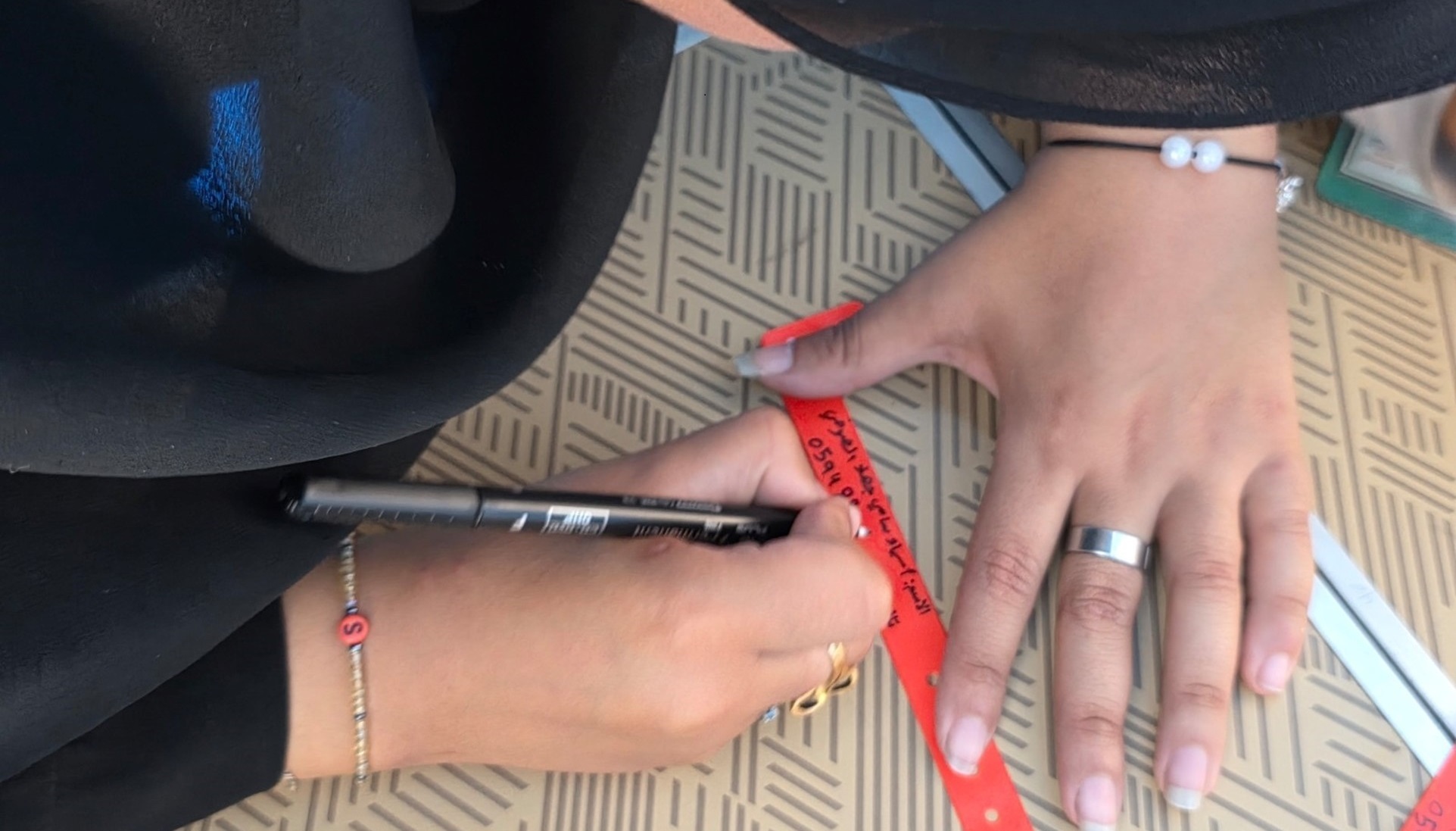 A mother write her phne number on an ID bracelet; }}