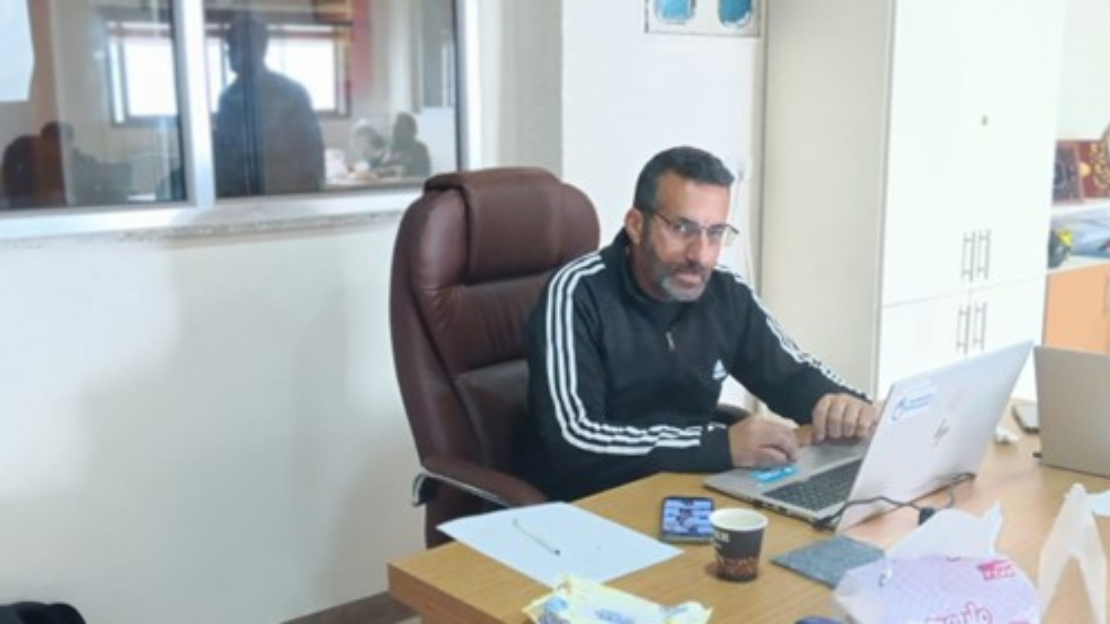 A man sitting at his desk; }}