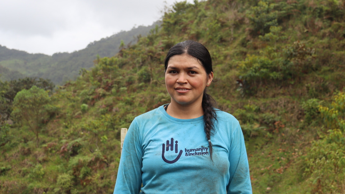 Portrait en gros plan d'une femme souriante, portant un polo avec le logo HI et la mention 