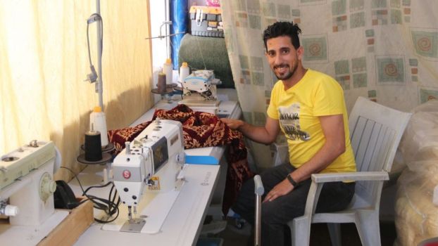29-year-old Ahmad sits in his sewing studio at home.; }}
