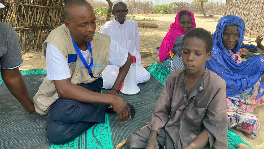 Mahamat with an HI agent in the displcaed people camp in Kousseri; }}