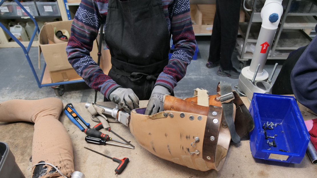 A Liimba project volunteer is dismantling a prosthesis to recover its components.