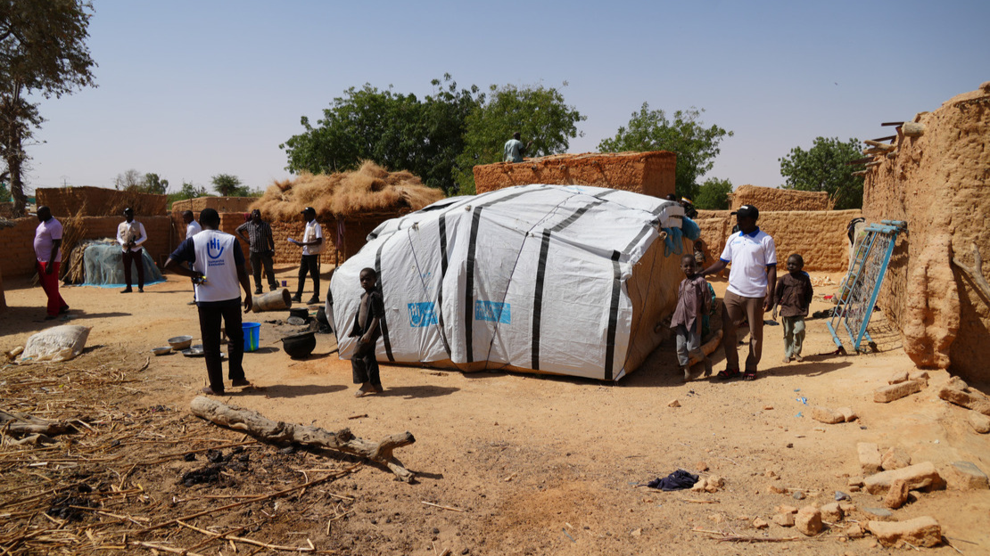 General view of the village with adults, children and a tent.; }}