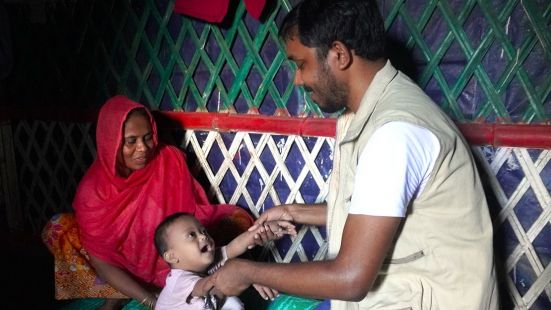 Ershad en pleine séance de réadaptation en présence de sa mère et du kinésithérapeute de HI Bangladesh dans le logement. 