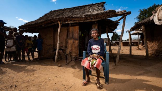 Nahy, 66 ans, est assise sur une chaise à l'extérieur de sa maison dans le sud de Madagascar.; }}