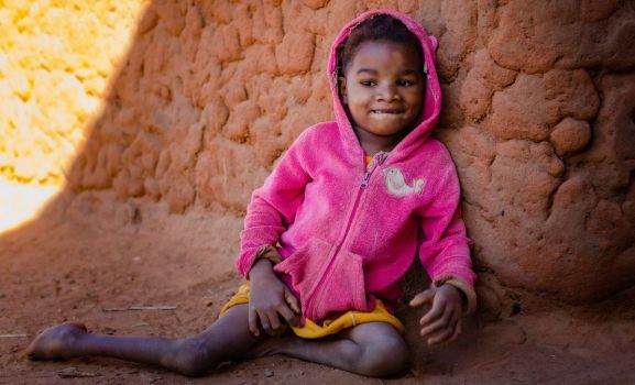 Avotavy, 9 ans, assise devant sa maison à Bezaha, Madagascar.; }}