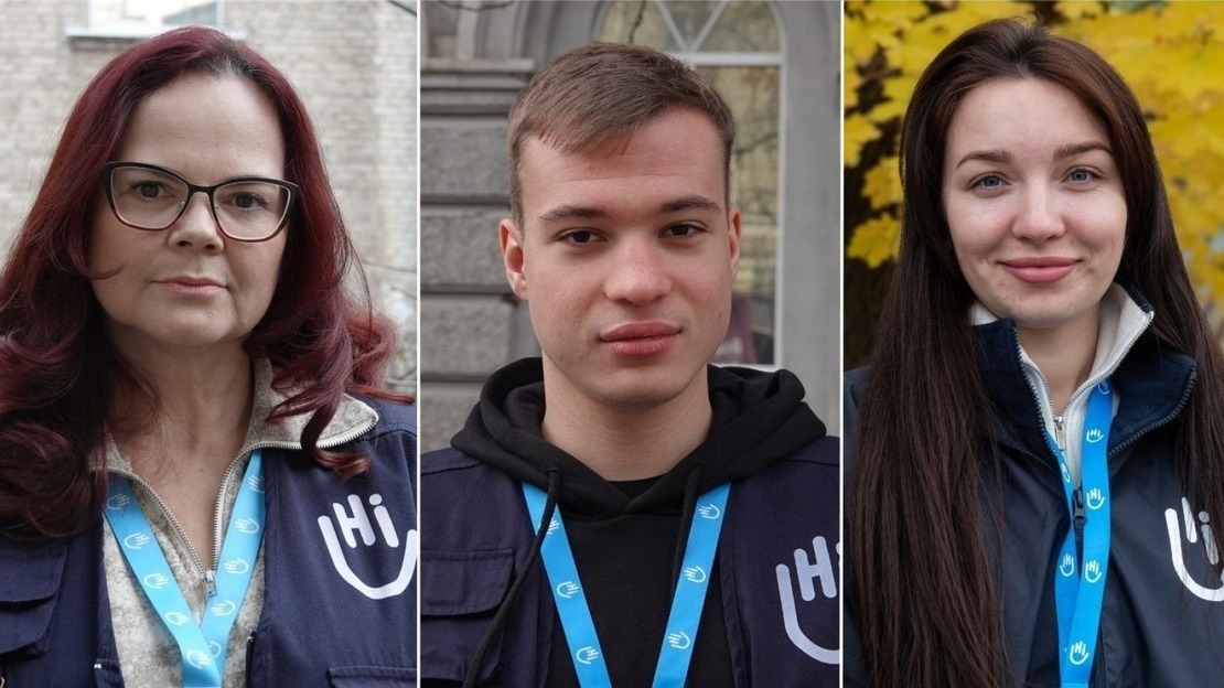 Trois portraits côte à côte montrent des membres de l’organisation humanitaire HI. À gauche, une femme aux cheveux roux et lunettes, portant un gilet bleu avec le logo HI et un badge autour du cou. Au centre, un jeune homme aux cheveux courts, vêtu d’un sweat noir sous son gilet HI. À droite, une jeune femme aux longs cheveux bruns, souriante, avec une veste HI.; }}
