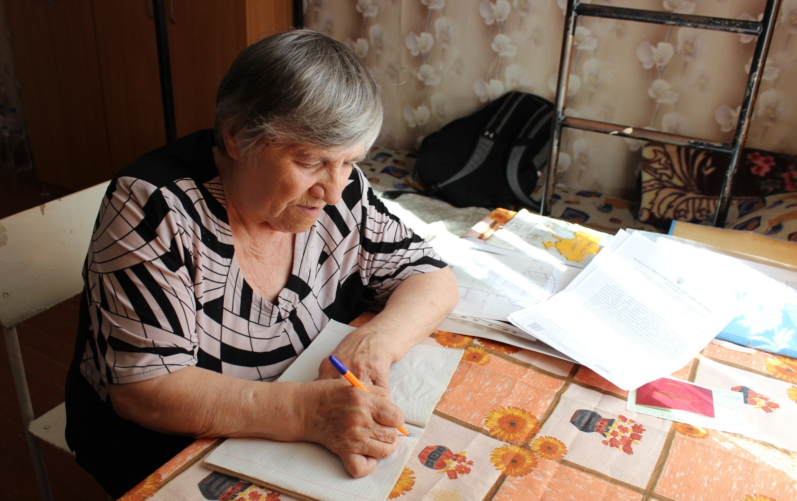 Lidiya Ivanivna, who suffered serious injuries to her right hand after a cluster munitions incident in March 2022 in the city of Dergachi, Kharkiv region, shows how she managed to regain the ability to write with her right hand, thanks to physical rehabilitation conducted by HI. September 2025. ; }}