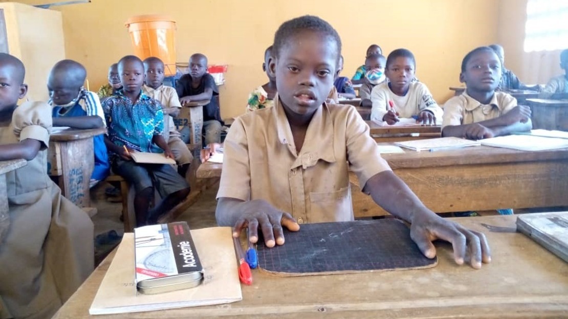Vincent est assis sur un banc d'école avec ses fournitures devant lui.