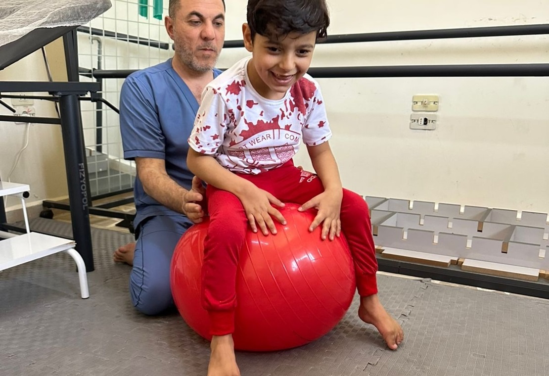 Qasim Al Ahmad, kinésithérapeute de HI, avec Hadi. ; }}