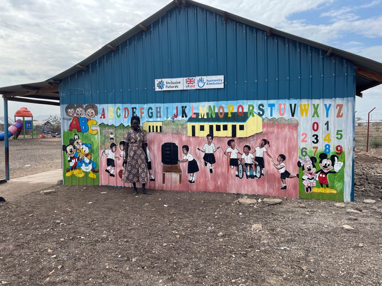 Susan devant une peinture murale dans une école maternelle de la colonie de Kalobeyei au Kenya.