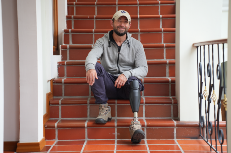 Andres sitting on stairs, with his prosthetic leg.