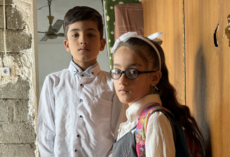 A boy and a girl standing in front of a door.